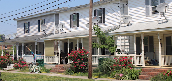 COUNT 'EM -- 10 satellite dishes on the front porch roof of these three row house duplexes consisting of six apartments. 