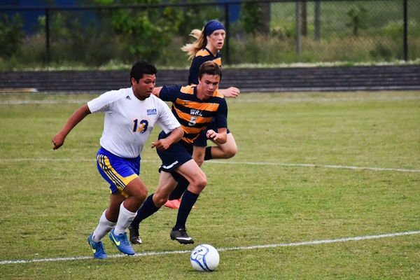 Number 13 Jesus Maldonado-Lopez drives past W&L’s Alec Westall and Jacob Daiger for a Jacket goal. (Photo: Chris 
